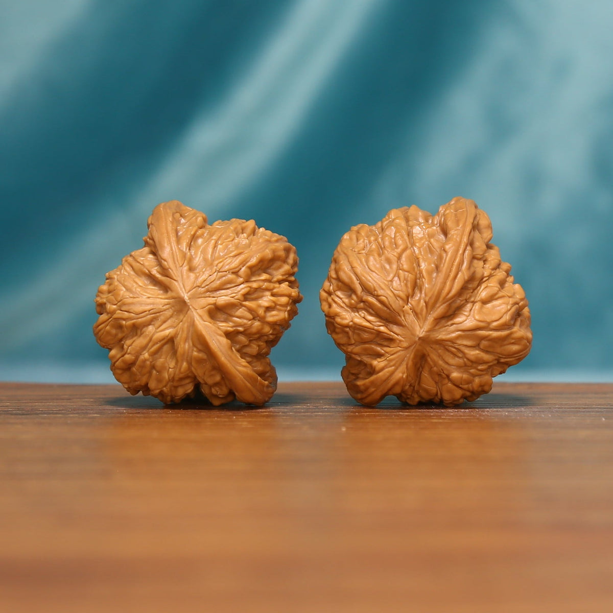 L17 Wenwan walnut pair shown from the side, highlighting radiating ridges and sculpted shell surfaces.
