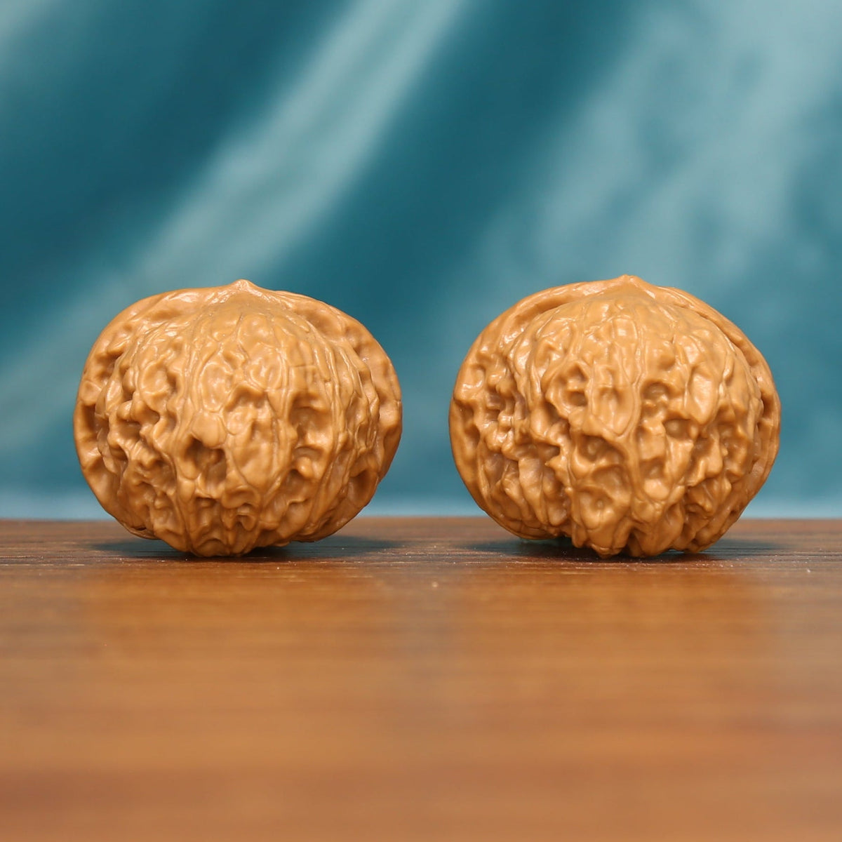 Angled front view of The Amber Drum Wenwan Walnuts showing warm amber color and richly textured surfaces.
