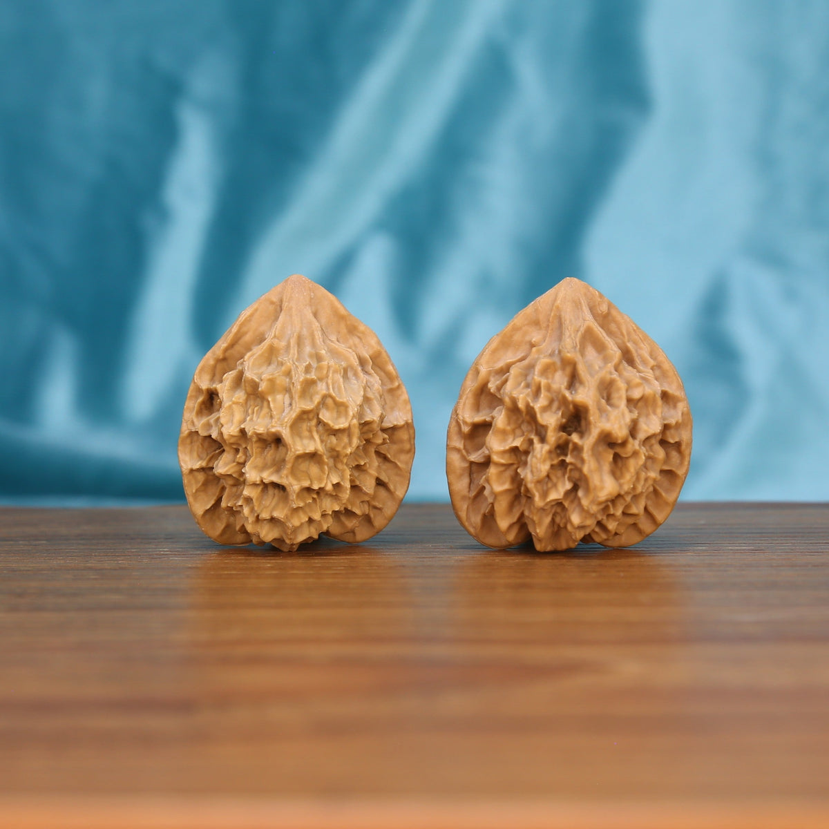 Single Di-Wang wenwan walnut on wooden surface, blue fabric background – tall spire-shaped natural texture