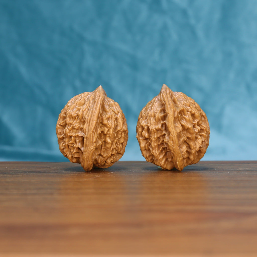 Side view of a Wheat Tiger Wenwan walnut pair on a wooden surface
