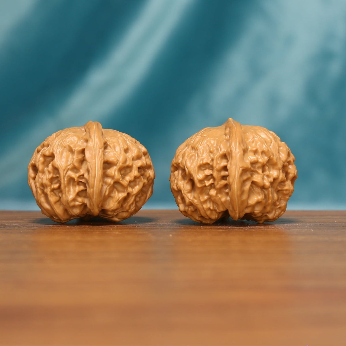 Distant front view of The Amber Drum Wenwan Walnut pair displayed on a wooden surface.
