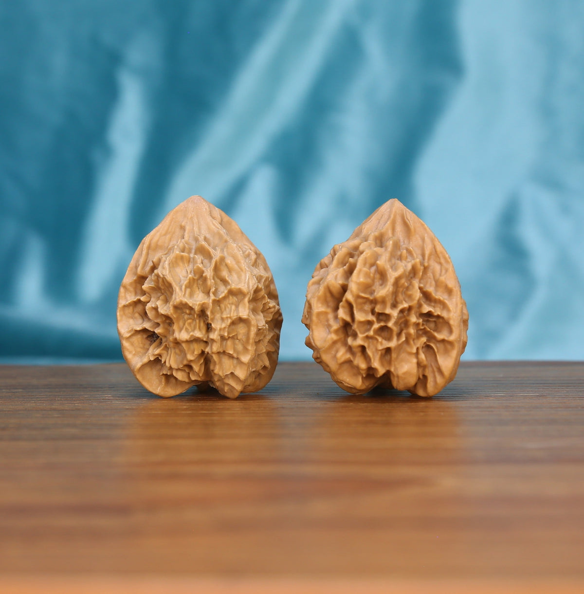 Two Di-Wang wenwan walnuts on wooden surface, blue background – matching sovereign spire set