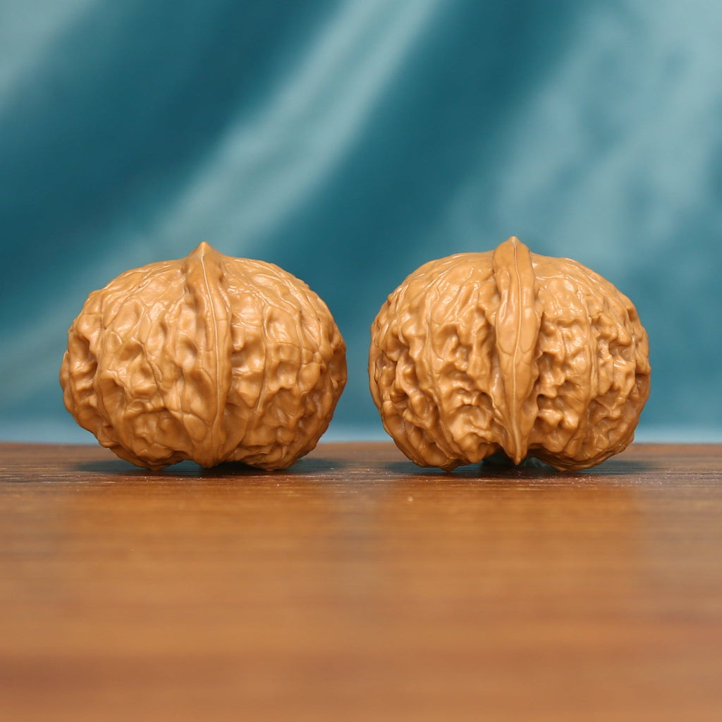 Side view of The Amber Drum Wenwan Walnuts highlighting their compact forms and deep natural ridges.
