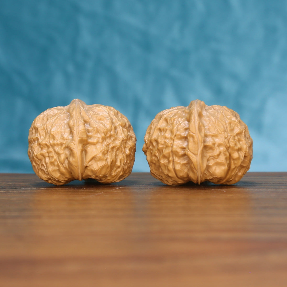 Close view of two matched pumpkin wenwan walnuts showing dense ridge carving and golden natural grain
