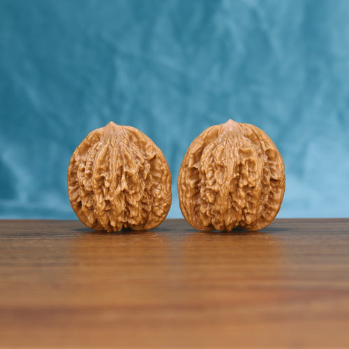 Front view of a matched pair of Wheat Tiger Wenwan walnuts with bold natural ridges
