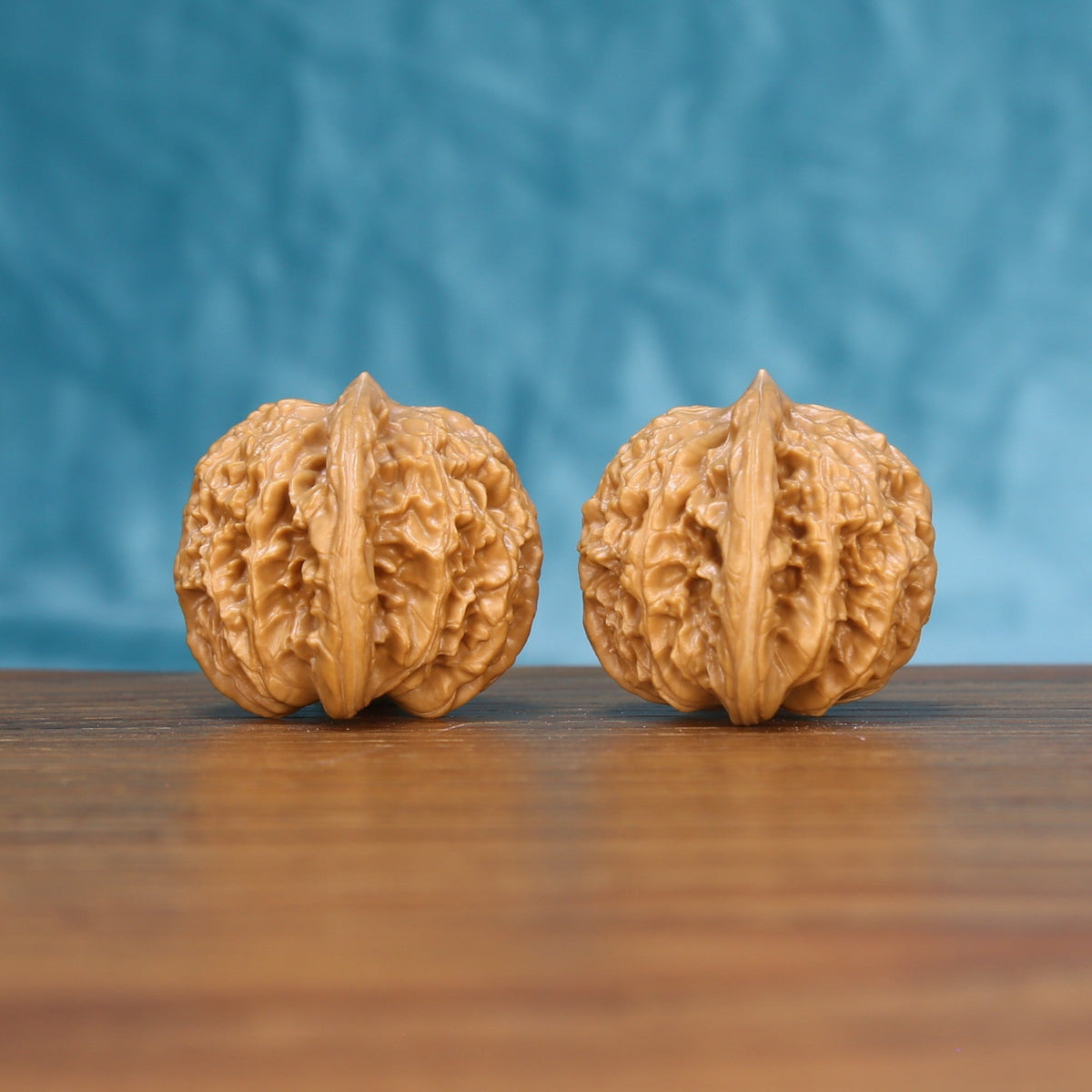 Side view of a Coiling Dragon Wenwan walnut pair on a wooden surface
