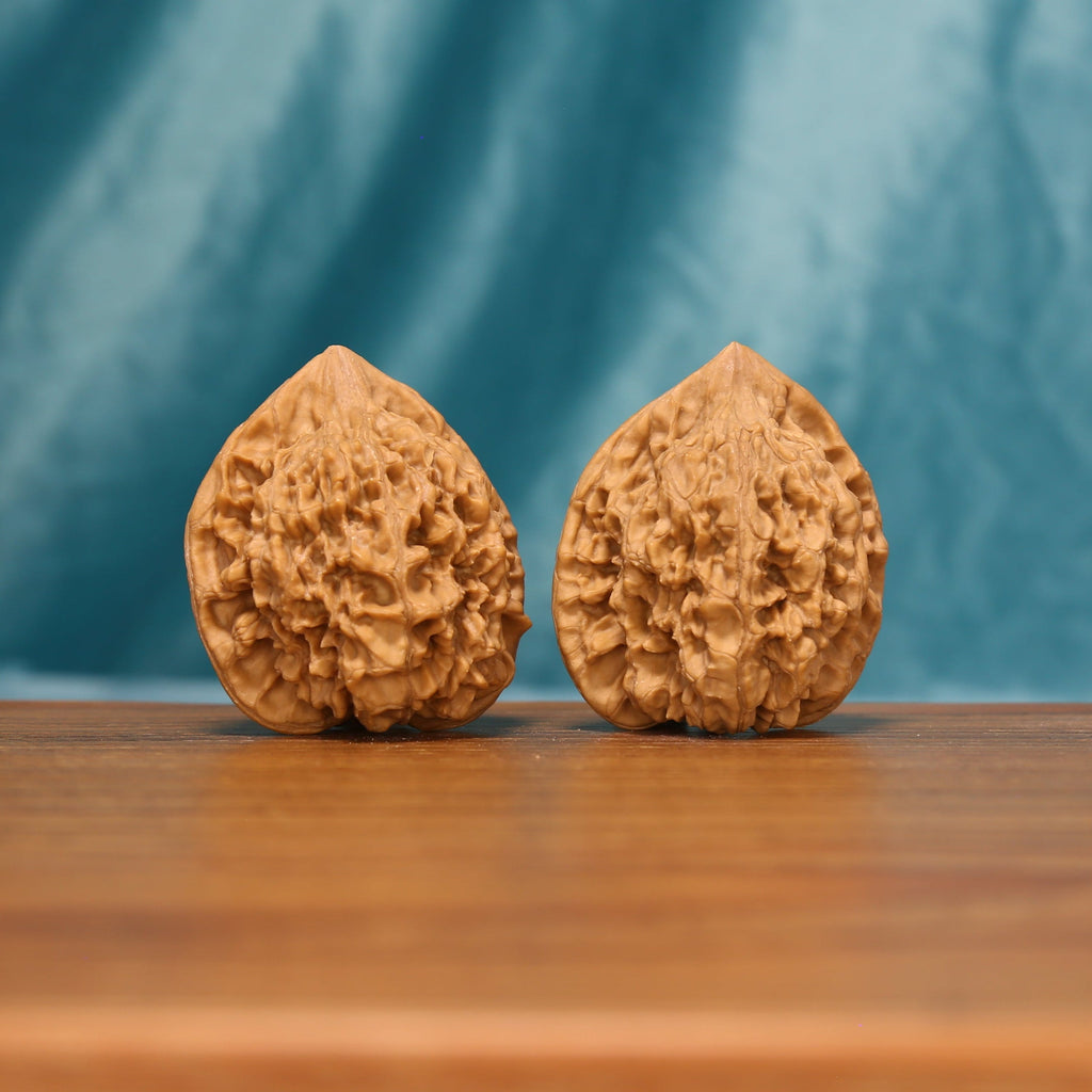 L22 Wenwan walnut pair shown from the front, highlighting elongated forms and dense natural ridge texture.
