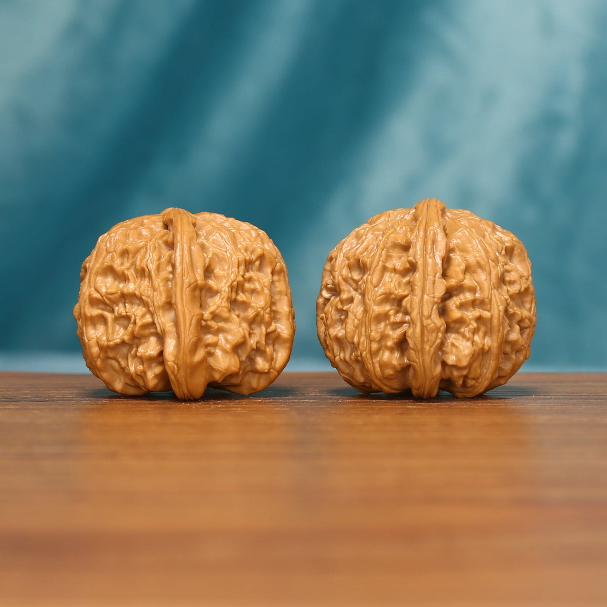 Side view of The Golden Basin Wenwan walnuts highlighting their compact forms and layered natural ridges.
