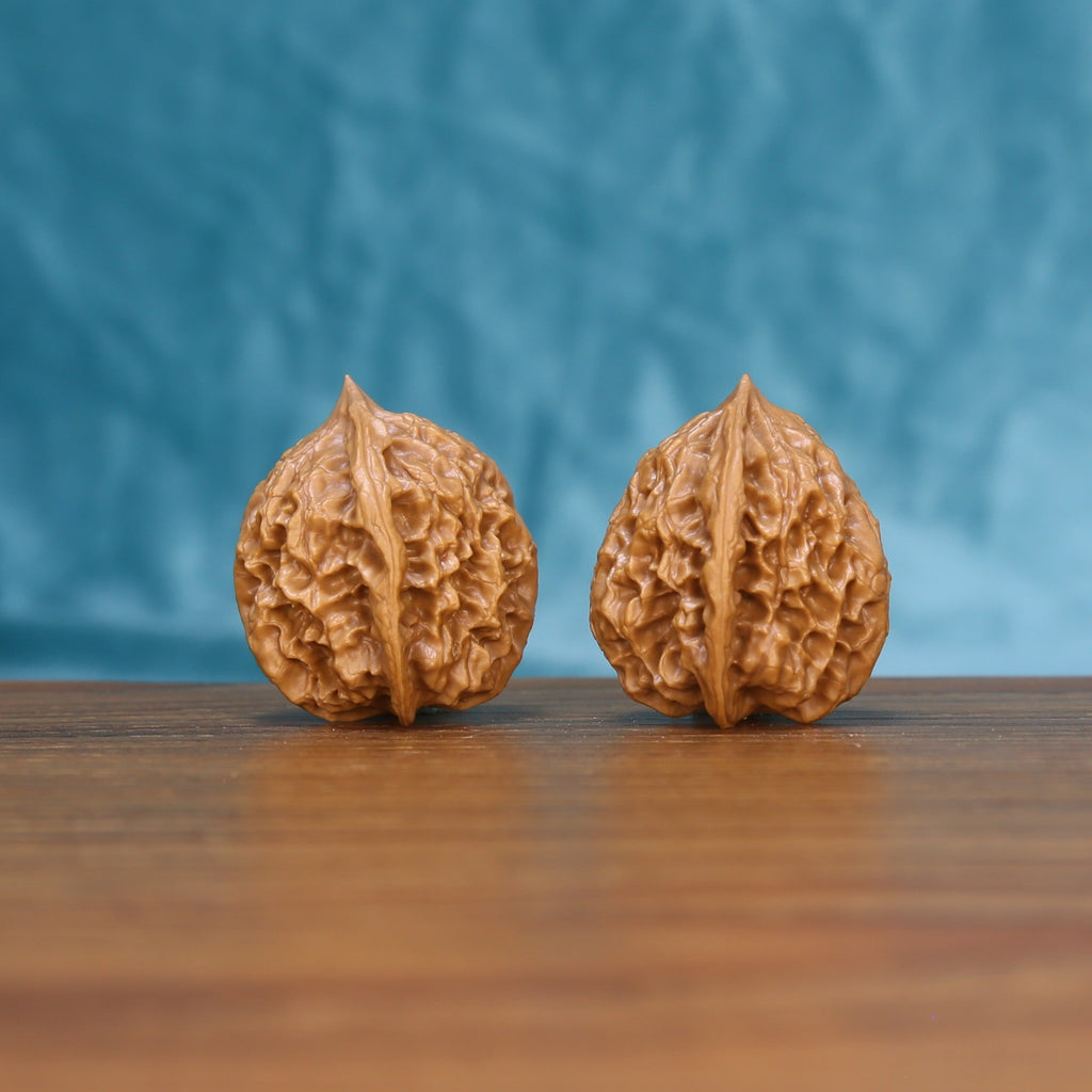 Side view of a Linglong Wenwan walnut pair on a wooden surface
