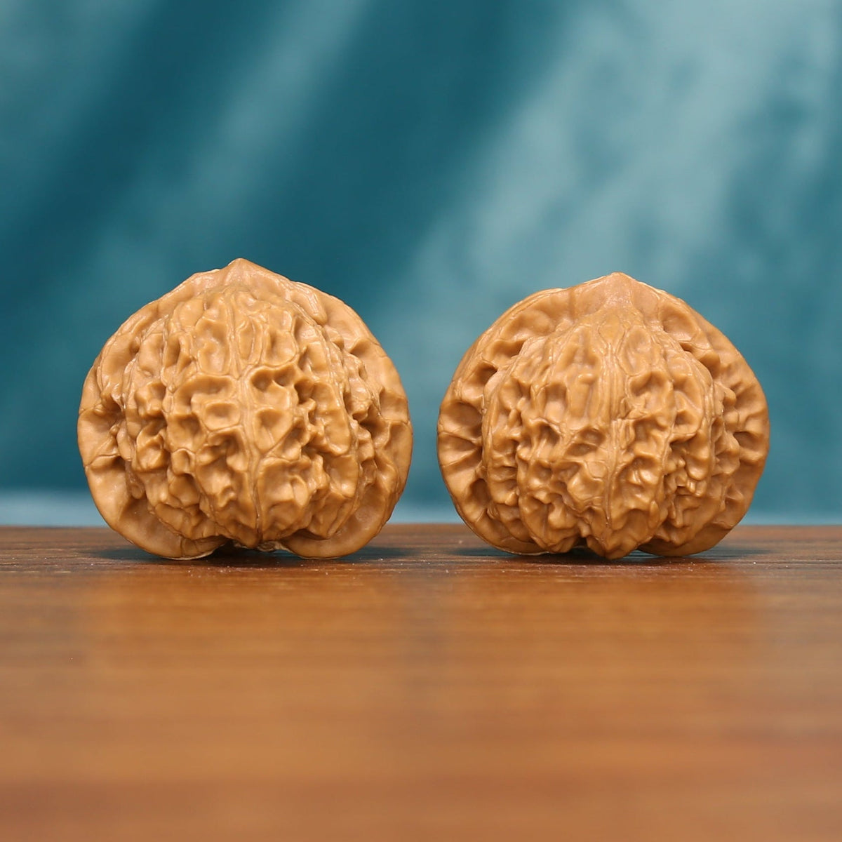 L20 Wenwan walnut pair shown from the front, highlighting rounded forms and natural ridge texture.
