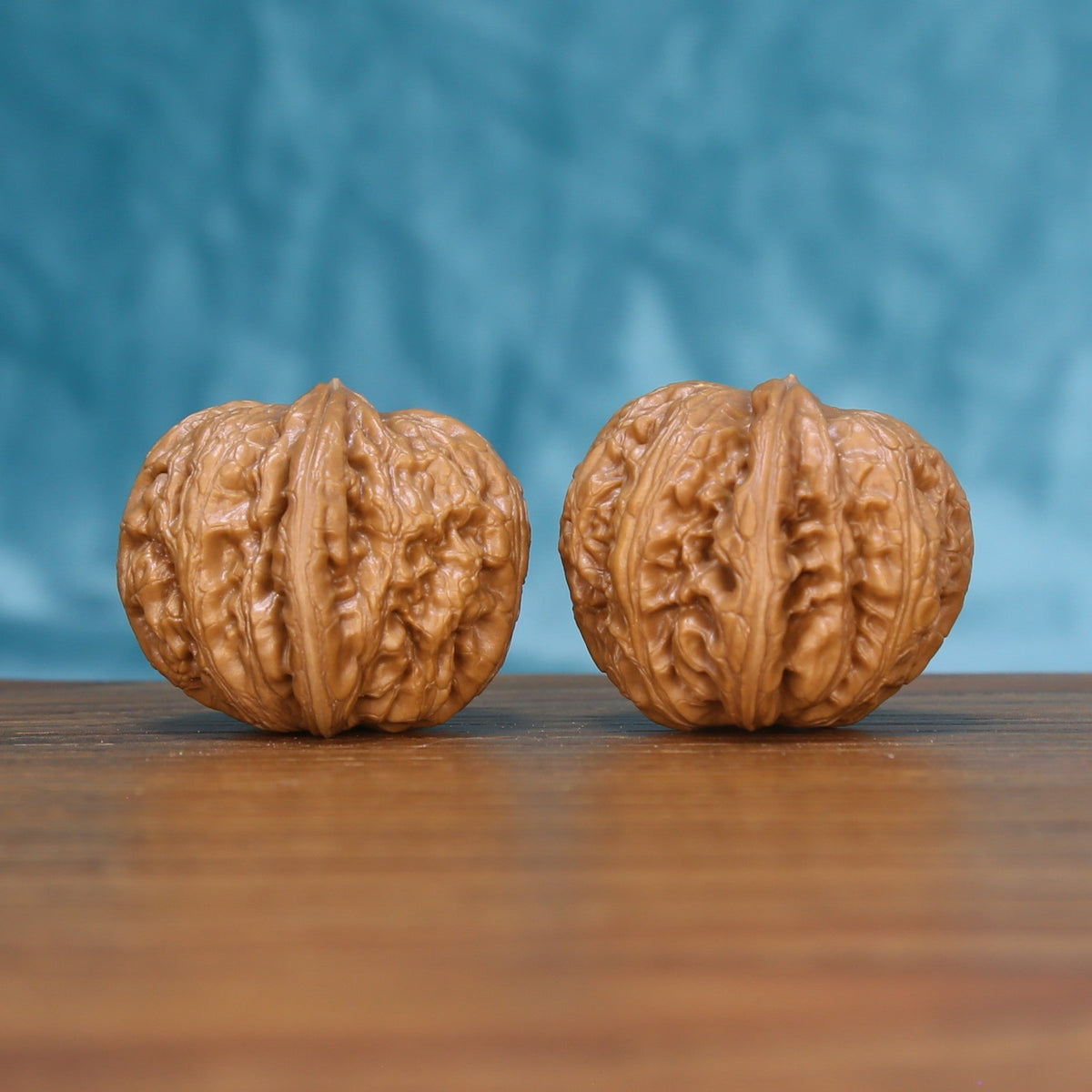 Three-quarter view of a Pinggu Yuanbao Wenwan walnut pair on a wooden surface
