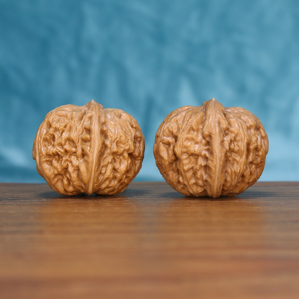 Close view of two matched Pinggu Ingot wenwan walnuts showing deep ridges and warm natural grain
