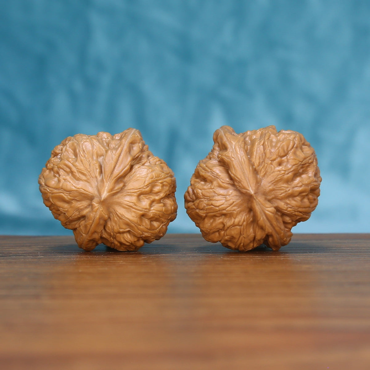 Side profile of the 6160 Pinggu Ingot wenwan walnut pair showing the raised central ridge
