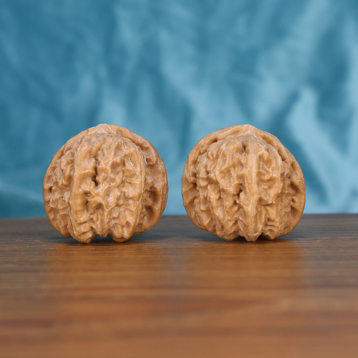 Two Bai-Shi-Zi wenwan walnuts on wooden surface, blue fabric background – matching alabaster mane set