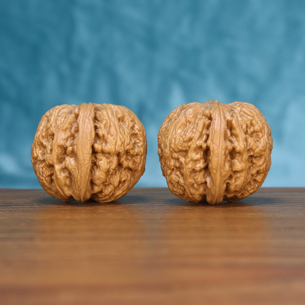 Three-quarter view of two General Wenwan walnuts showing deep sculptural ridges
