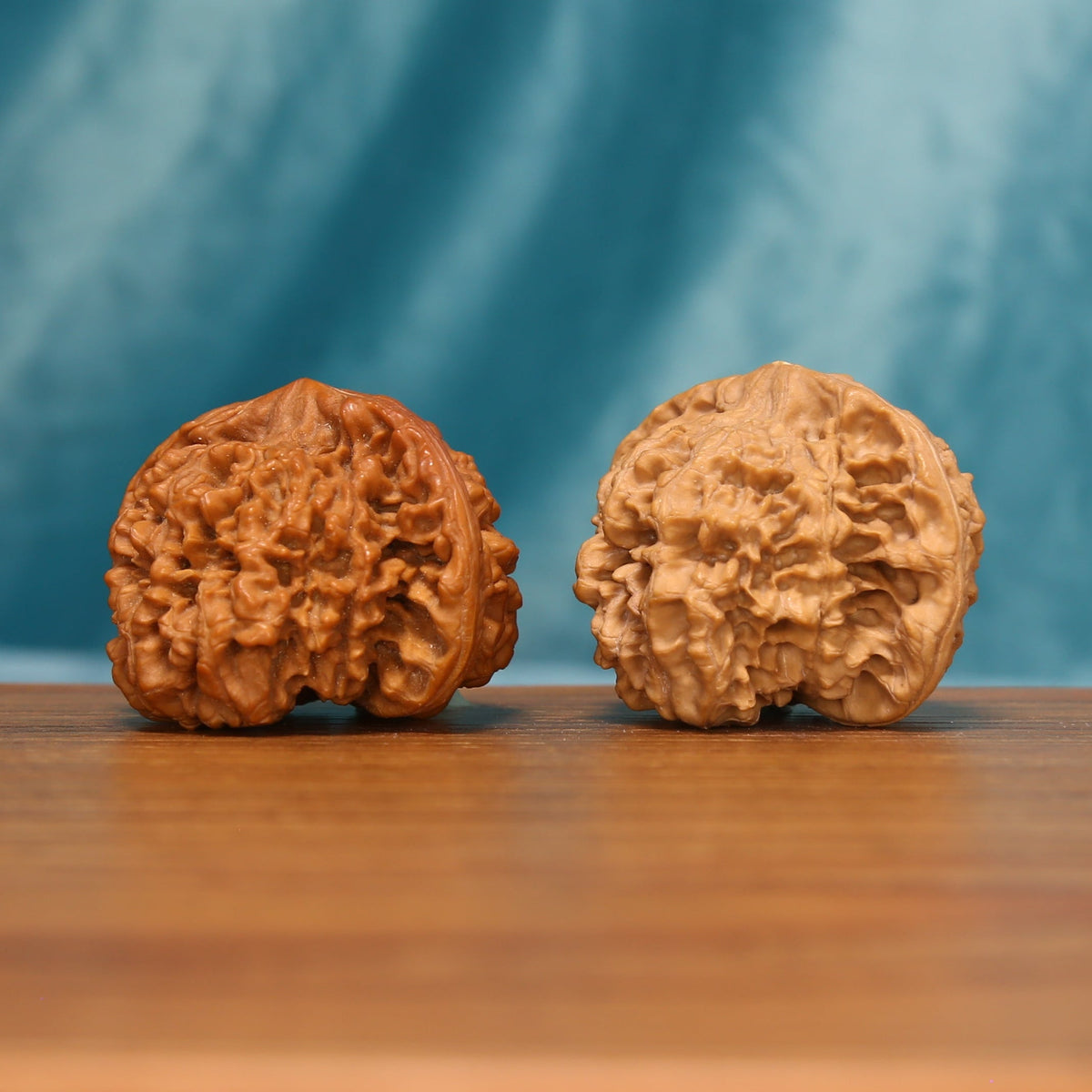 Detailed side view of The Yin-Yang Crown Wenwan walnuts displaying their distinct ridge patterns and natural variation.
