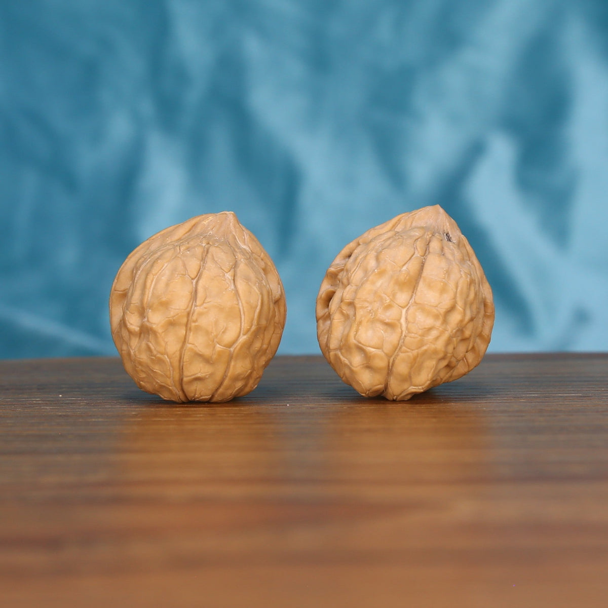  Two Gui-Jia-Wen wenwan walnuts on wooden surface, blue fabric background – matching carapace crest set