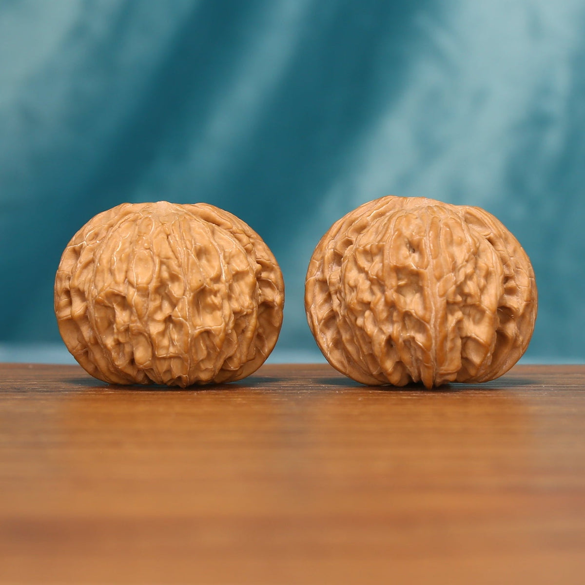 Carved Millstones Wenwan walnut pair shown from an angled front view with rounded forms
