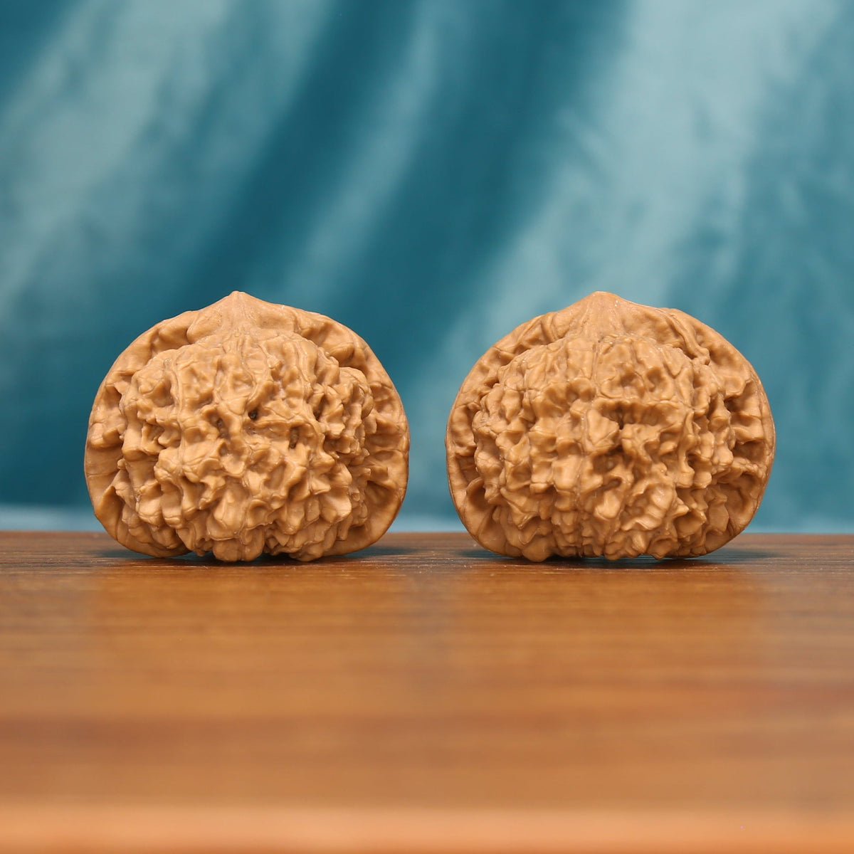 Front view of The Capstone Pair Wenwan Walnut Set showing two large rounded walnuts with capped crown forms.

