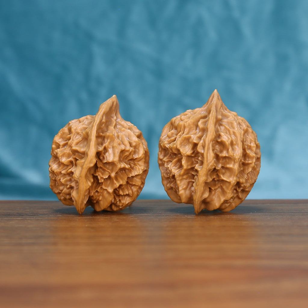 Close view of two matched Emperor wenwan walnuts showing sharp ridge carving and warm natural grain

