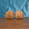 Two Qi-Da-Hai San-Leng wenwan walnuts on wooden surface, blue fabric background – matching tri-star geometry set