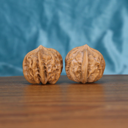 Two Qi-Da-Hai San-Leng wenwan walnuts on wooden surface, blue fabric background – matching tri-star geometry set