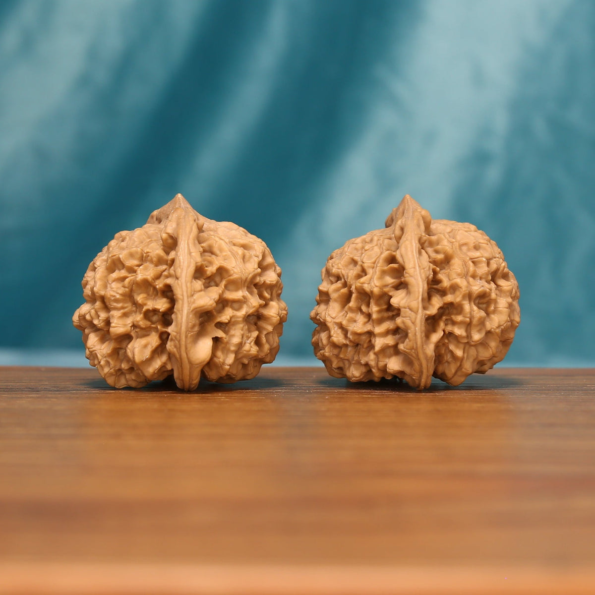 Detailed side view of The Capstone Pair Wenwan walnuts with sculpted surfaces and natural variation.
