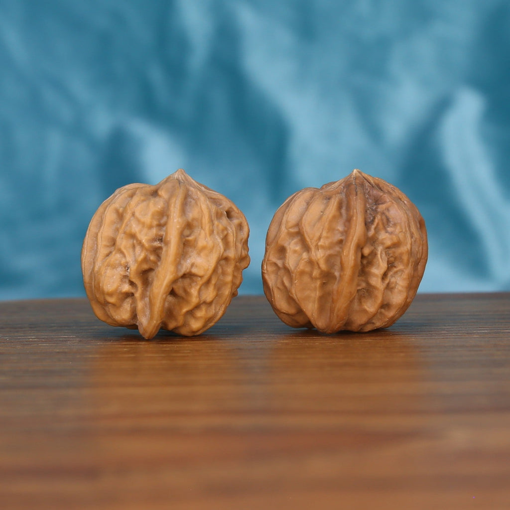 Two Qi-Da-Hai San-Leng wenwan walnuts on wooden surface, blue fabric background – matching tri-fold labyrinth set
