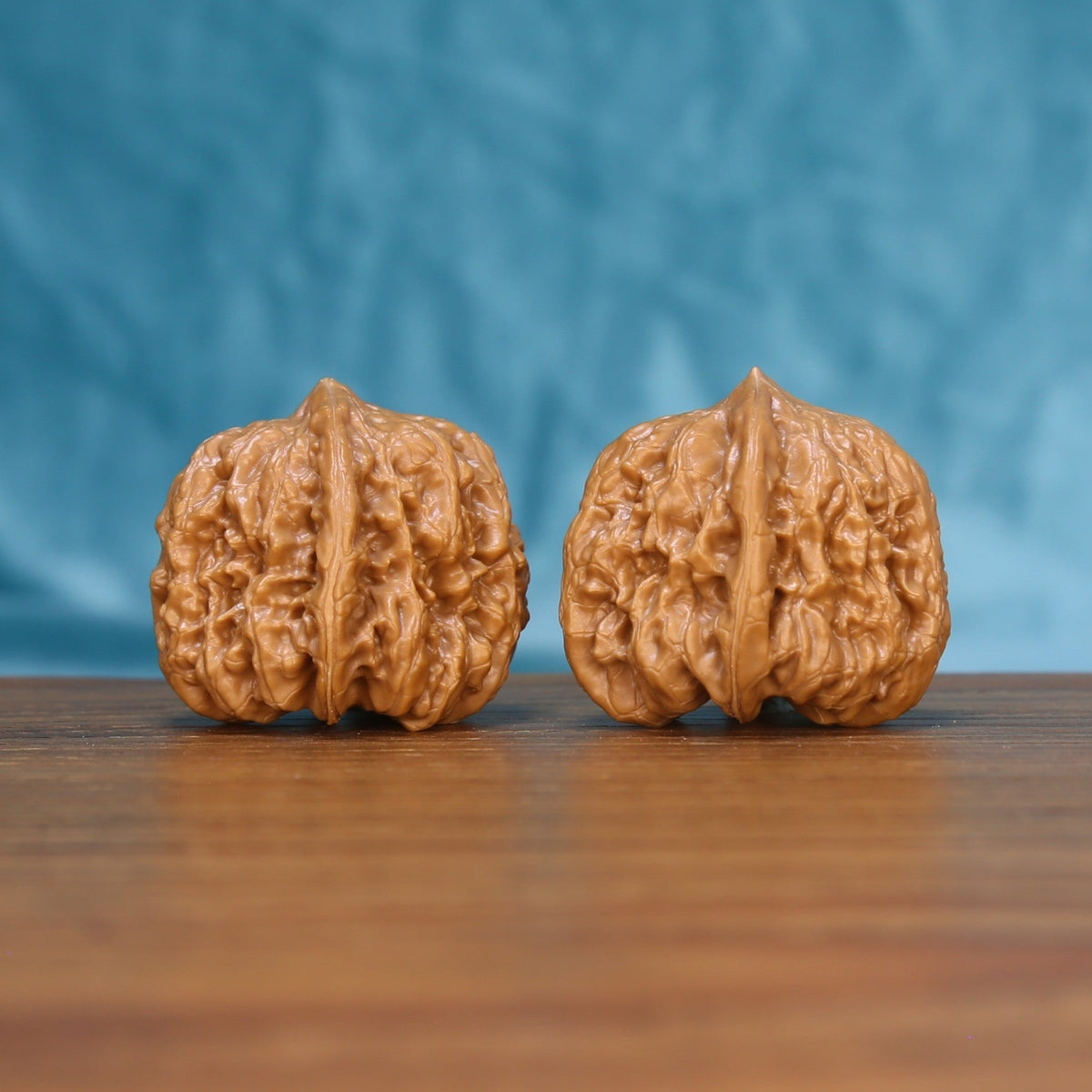Side view of a Pinggu Concave Base Wenwan walnut pair on a wooden surface
