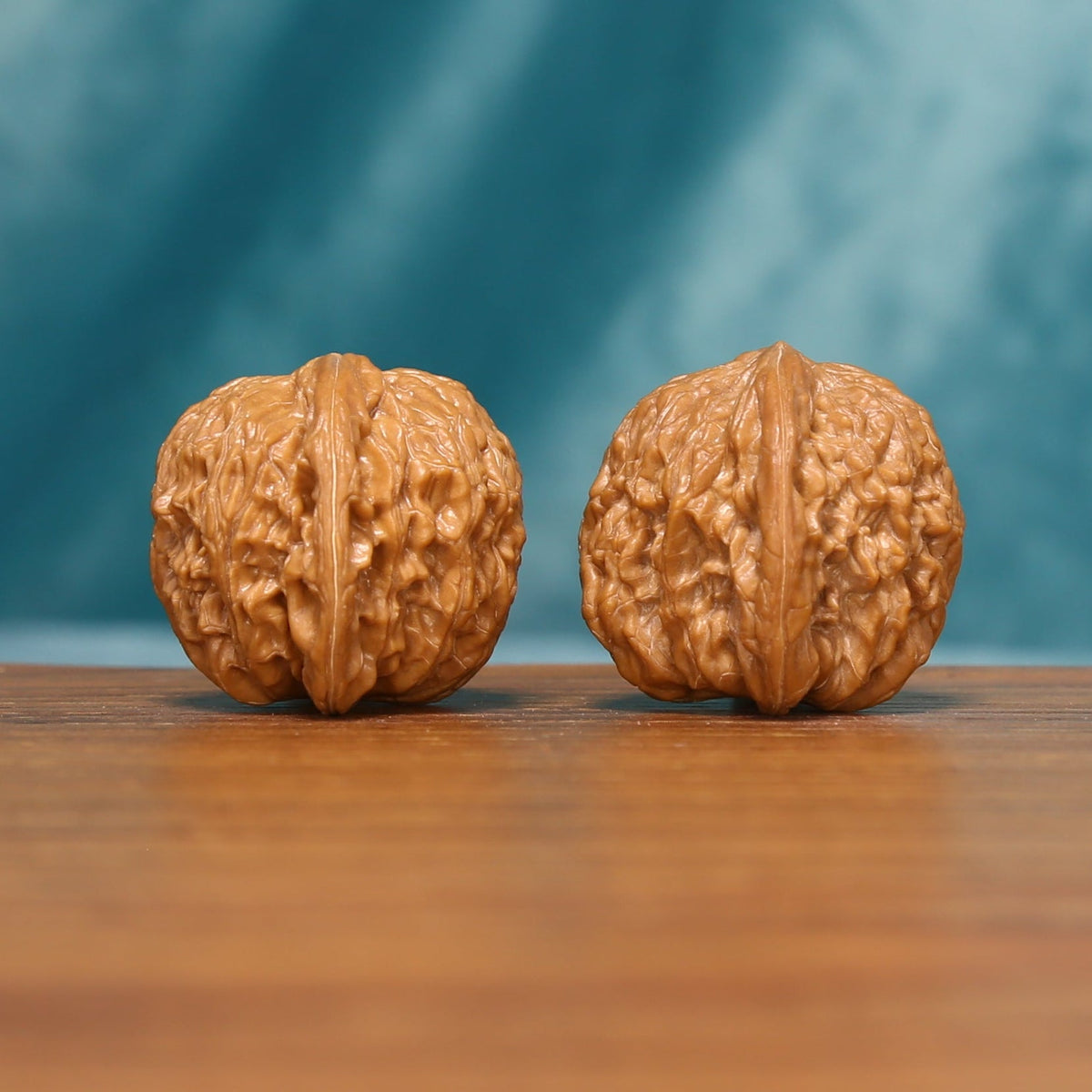 Twin Millstones Wenwan walnut pair shown from the side with detailed textured surfaces
