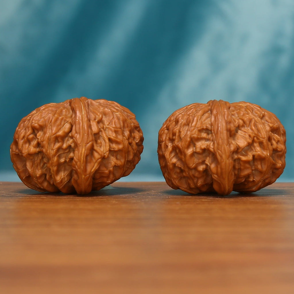 Millstone Wenwan walnut pair shown from an angled view highlighting the deep carved ridges
