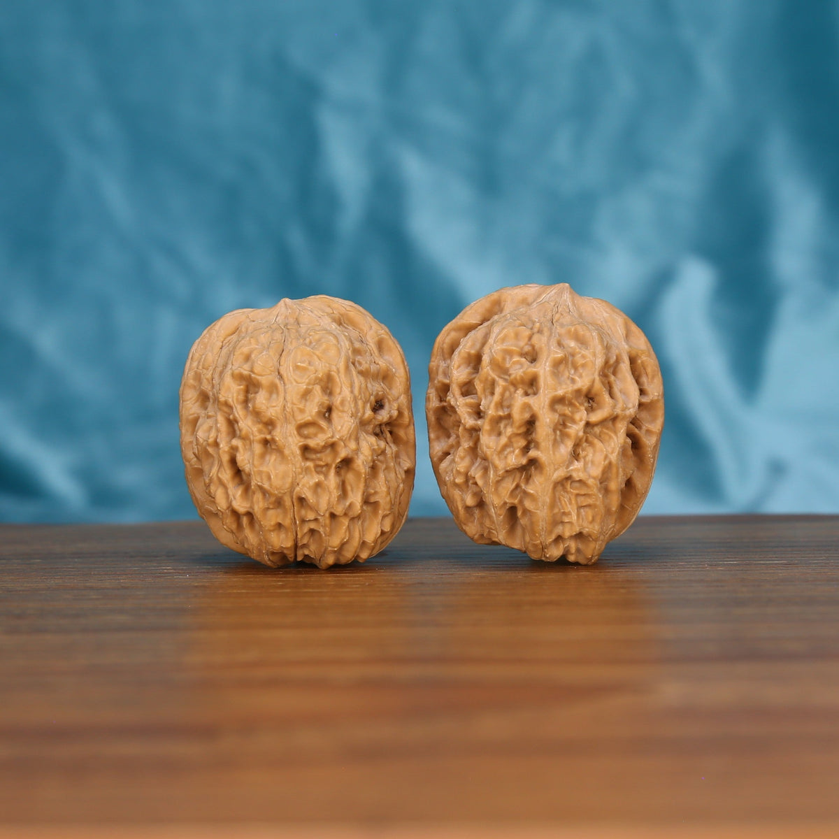 Xi-Bei Jiang-Jun-Bang walnut set side profile on wood, blue background – elongated general's club grain detail