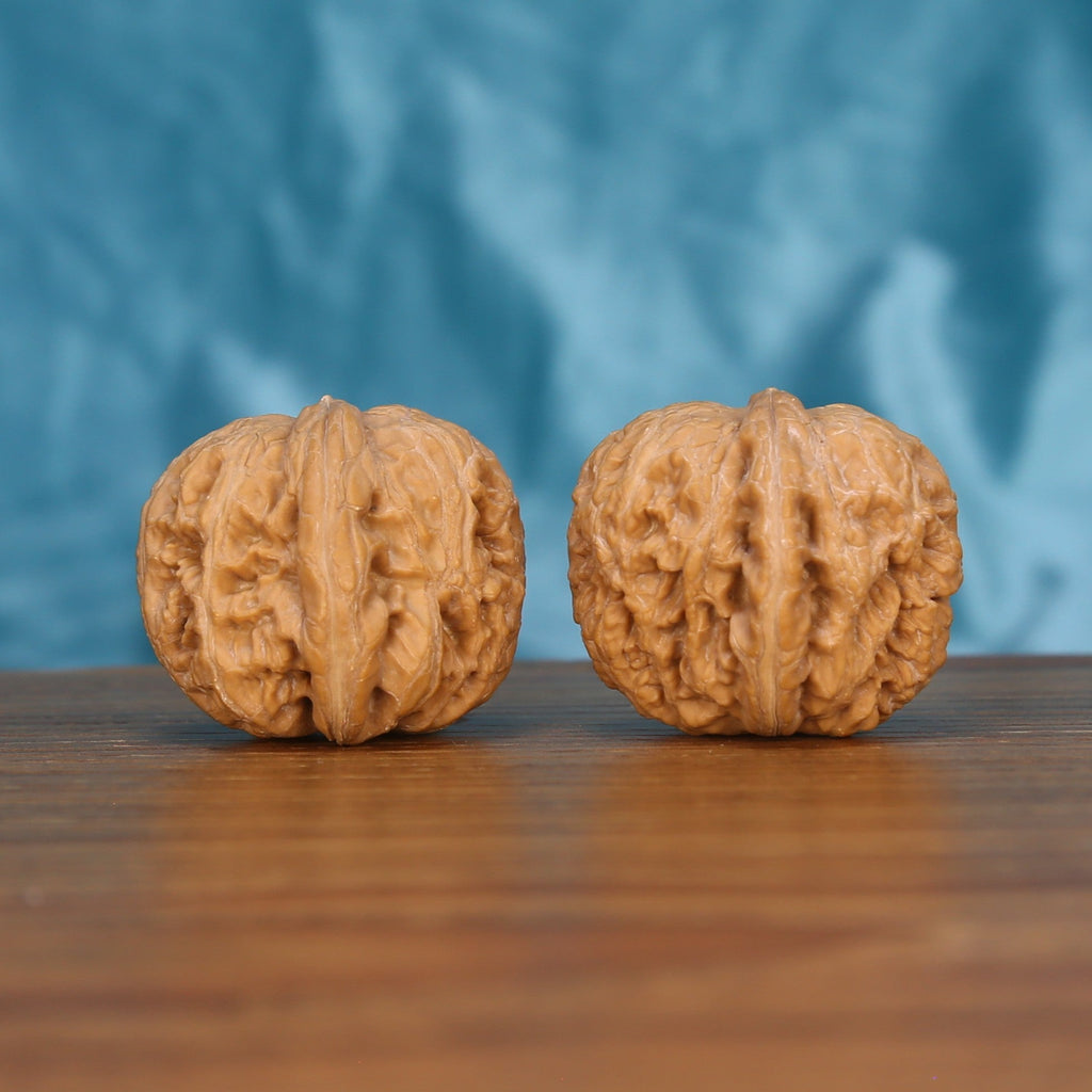 Ping-Gu-Yuan-Bao walnut set side profile on wood, blue background – symmetrical wealth-curve grain detail