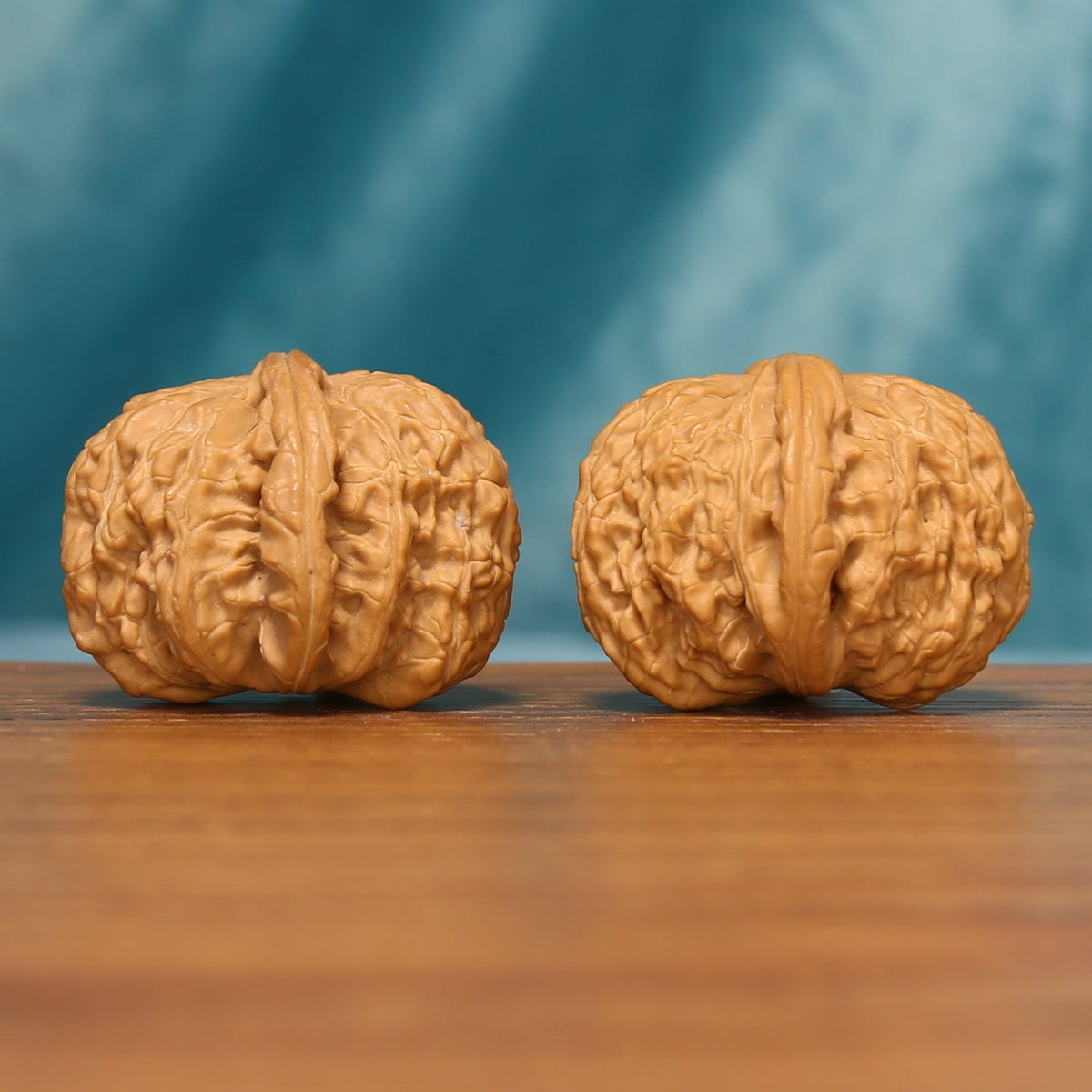 Side view of the White Lion Head Wenwan walnuts highlighting their sculpted profiles and intricate ridge patterns.

