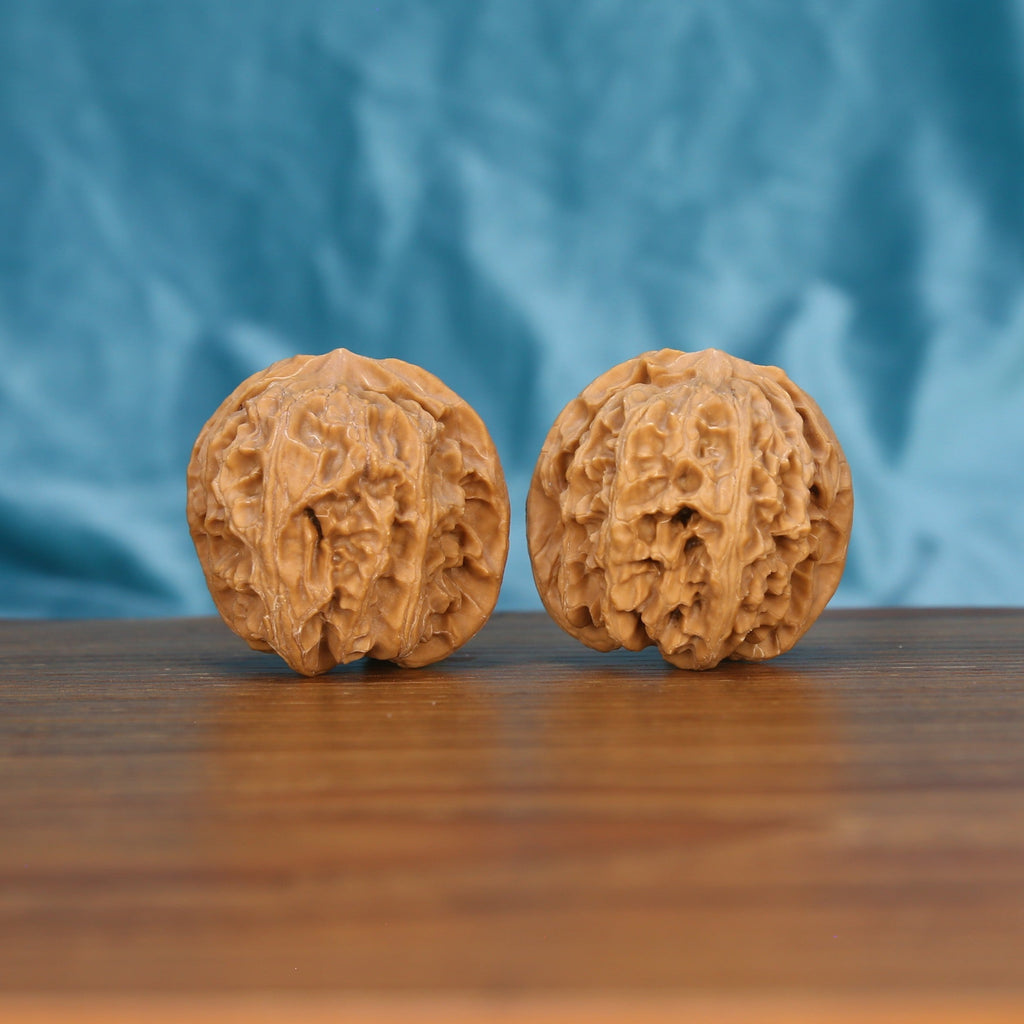 Two Ping-Guo-Yuan wenwan walnuts on wooden surface, blue fabric background – matching pure equilibrium set