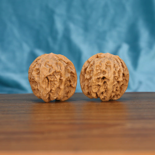 Two Ping-Guo-Yuan wenwan walnuts on wooden surface, blue fabric background – matching pure equilibrium set