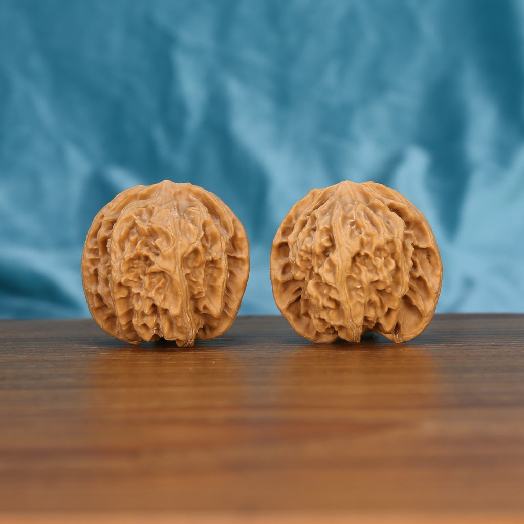 Ping-Guo-Yuan walnut set side profile on wood, blue background – symmetrical apple-round grain detail