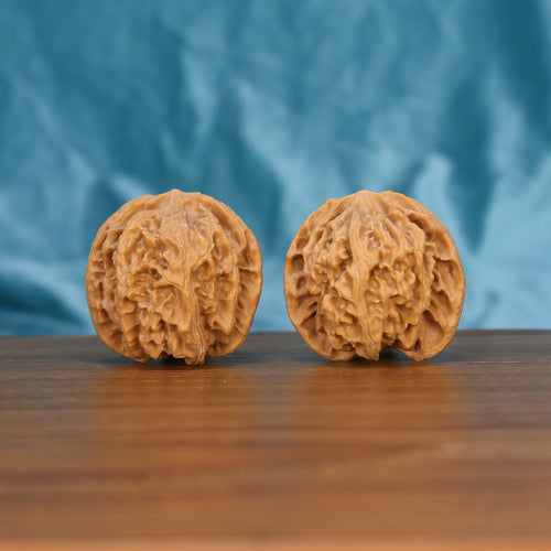 Ping-Guo-Yuan walnut set side profile on wood, blue background – symmetrical apple-round grain detail
