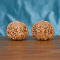 Two Ping-Gu-Ao-Di wenwan walnuts on wooden surface, blue fabric background – matching sunken center set