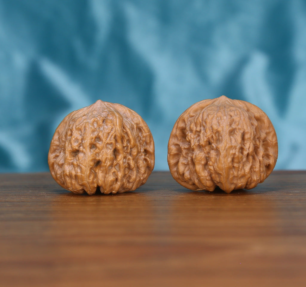 Ping-Gu-Ao-Di walnut set side profile on wood, blue background – round sphere with sunken top grain detail