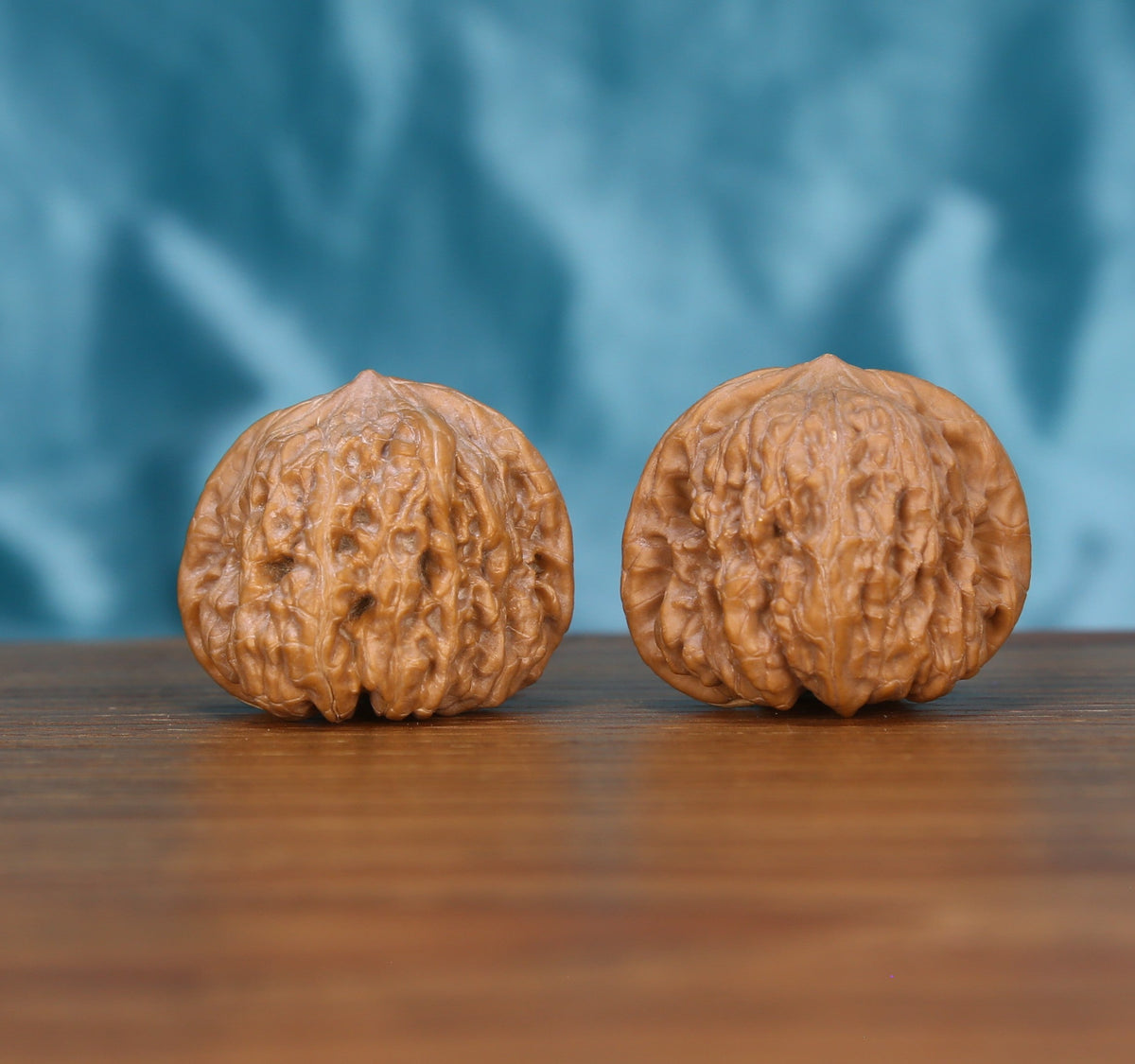 Ping-Gu-Ao-Di walnut set side profile on wood, blue background – round sphere with sunken top grain detail