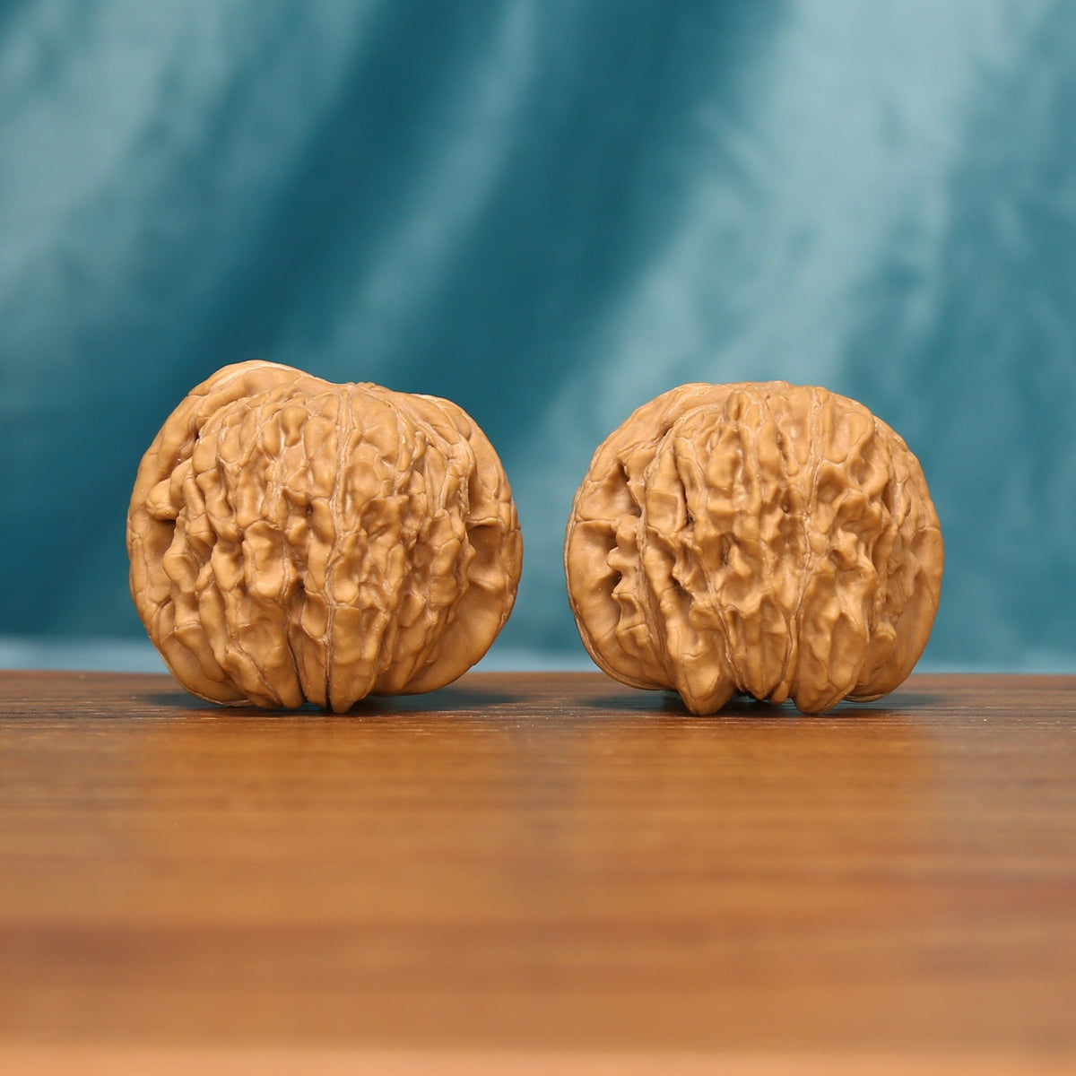 Huakun Dragon Wenwan walnut pair shown from an angled front view with detailed carved ridges
