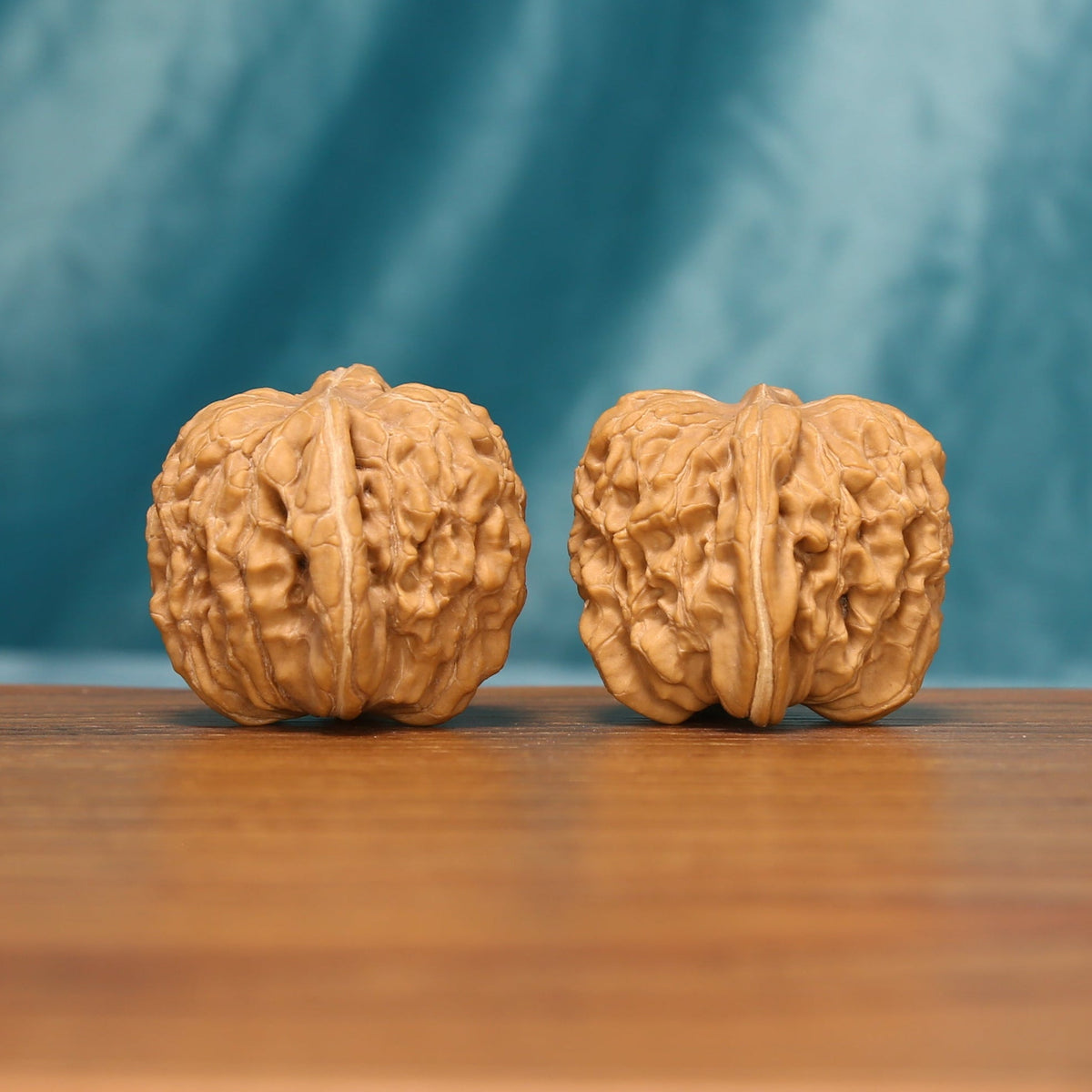 Huakun Dragon Wenwan walnut pair shown from the side with symmetrical carved patterns

