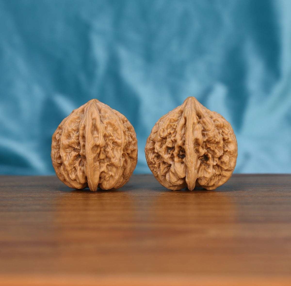 Single Da-Cu-Jin wenwan walnut on wooden surface, blue background – bold rough-gold natural texture close-up