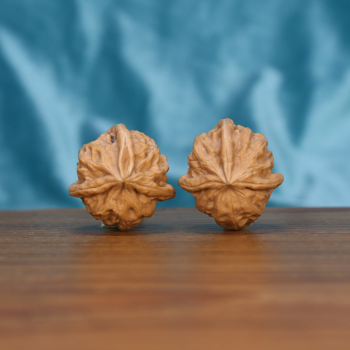 Two Qi-Da-Hai San-Leng wenwan walnuts on wooden surface, blue fabric background – matching trifold geometry set
