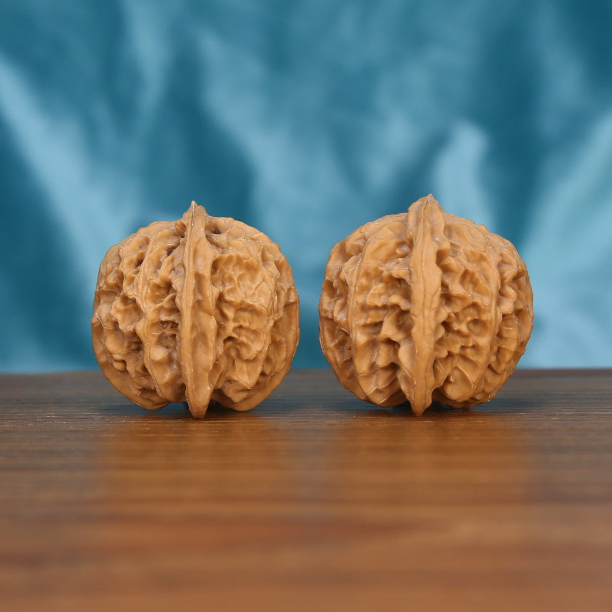 Ping-Guo-Yuan walnut set side profile on wood, blue background – symmetrical apple-round grain detail