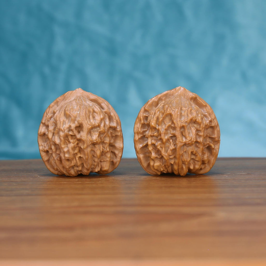 Two Jiang-Jun-Bang wenwan walnuts on wooden surface, blue fabric background – matching general's armor set