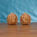 A perfectly matched pair of highly textured Wenwan Walnuts resting on a warm wooden surface against a tranquil blue backdrop. Serving as a tangible physical anchor and tactile meditation tool for digital detox.