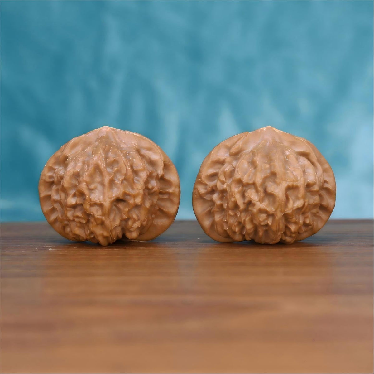 Two Gong-Deng wenwan walnuts on wooden surface, blue fabric background – matching architect's pavilion set