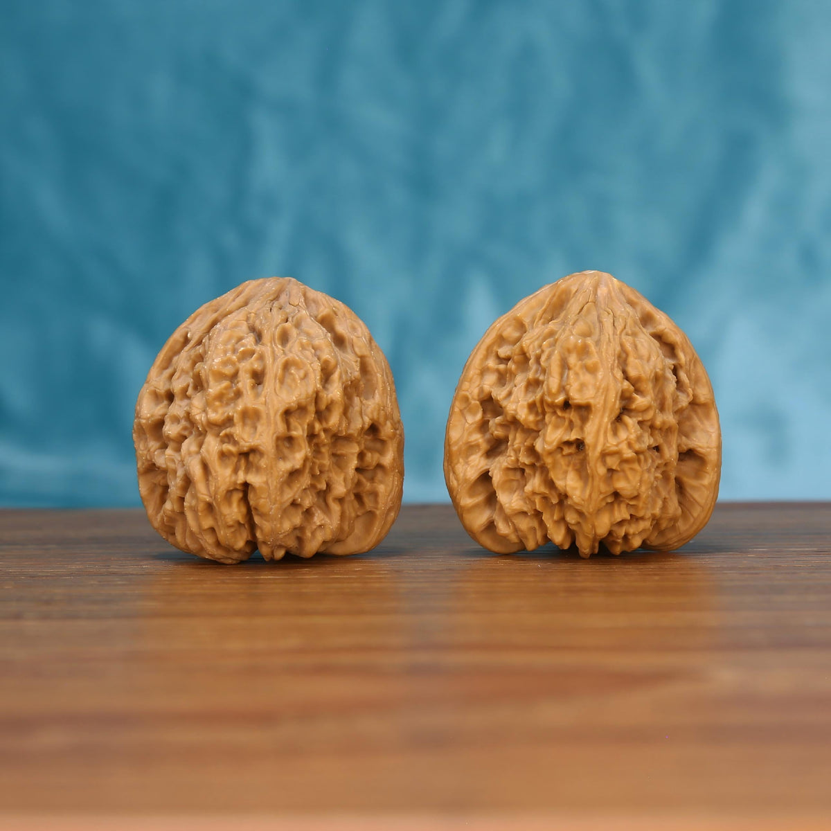 Two Nan-Jiang-Shi wenwan walnuts on wooden surface, blue fabric background – matching ancient bedrock set